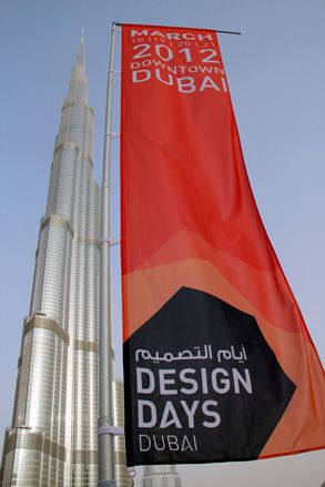 The red, black and white Design Days Dubai fabric banner blowing in the wind with a view of the Burj Khalifa skyscraper in the background during the day