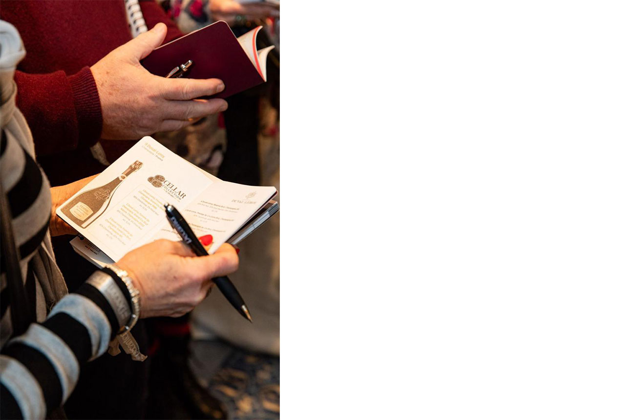 Hand holding tasting notes booklet and a pen