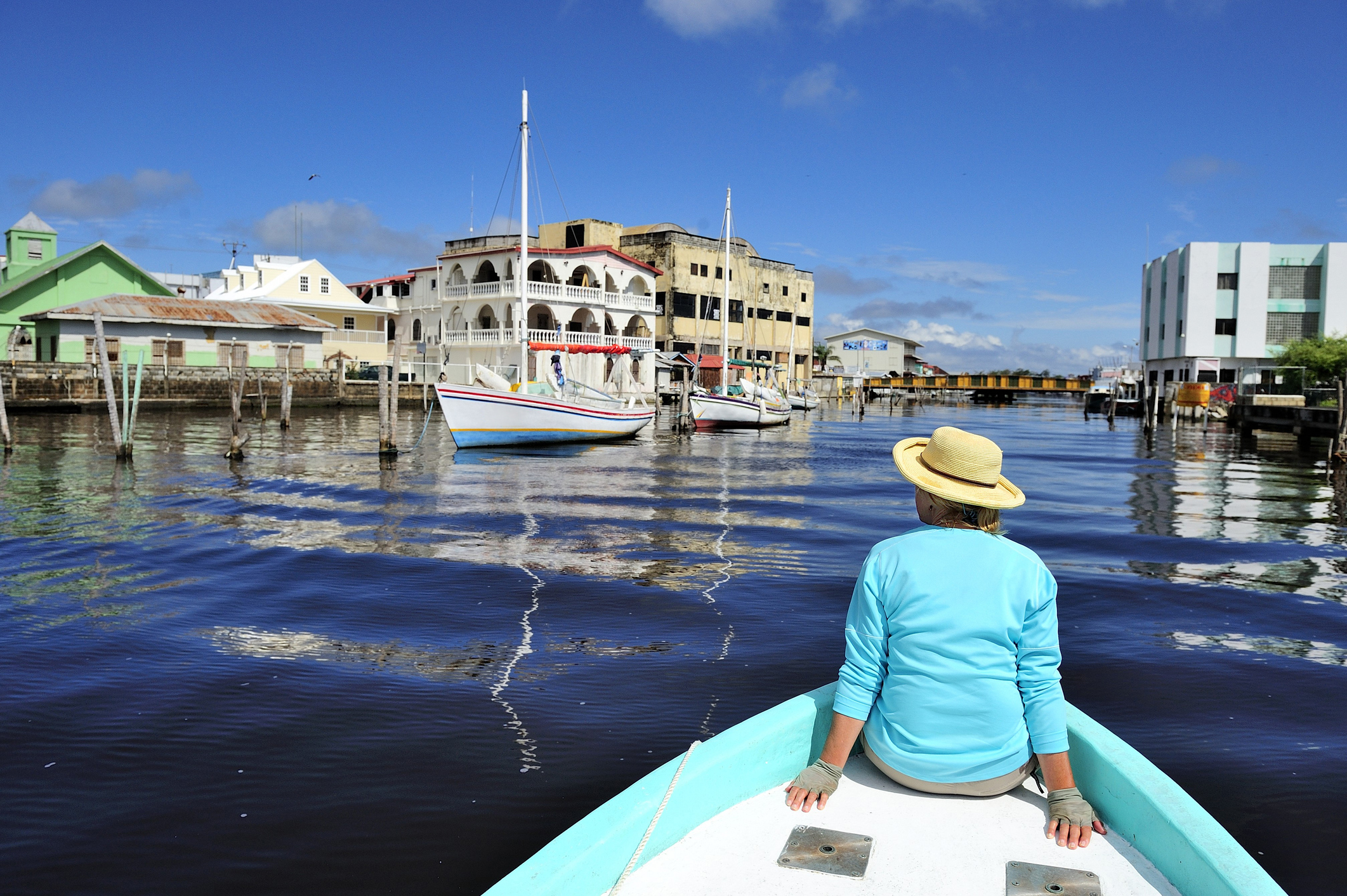 A woman tours through Belize City on the bow of a fishing boat.