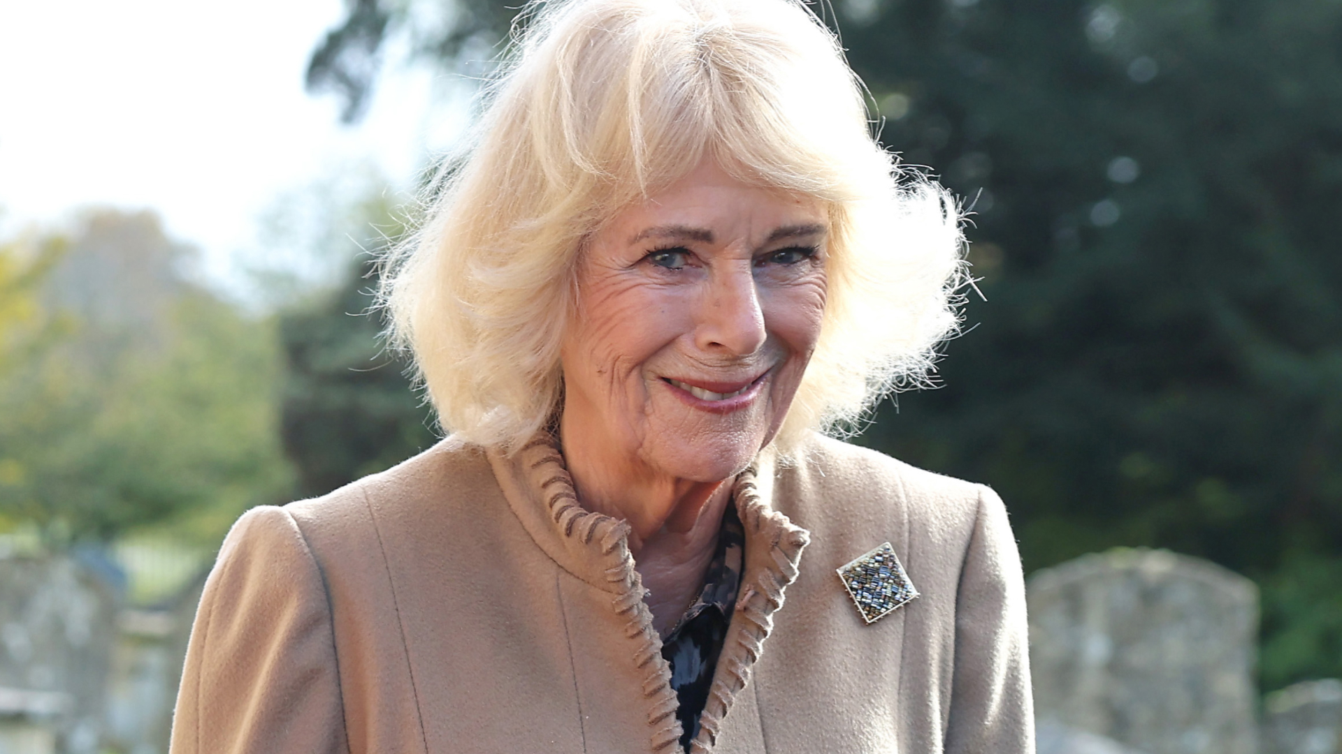 Queen Camilla wears a beige coat with a brooch