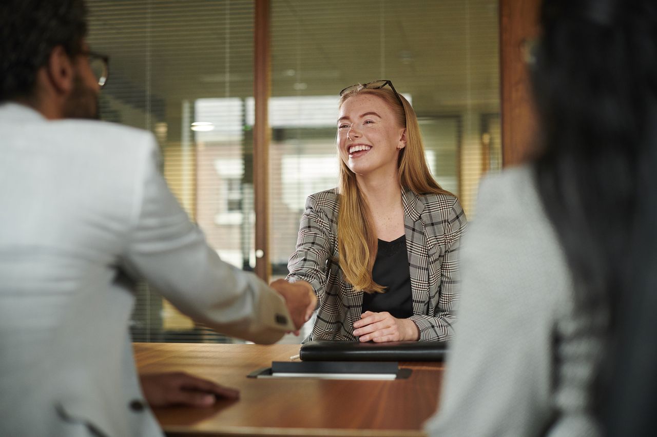 Recruitment process featuring interviewee smiling as she shakes hands with interviewer