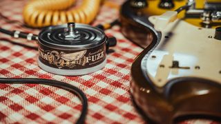 Beetronics Tuna Fuzz pedal on a table next to an electric guitar