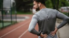Exercising with sciatica: Image shows man in sports gear holding lower back