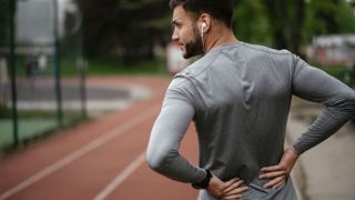 Exercising with sciatica: Image shows man in sports gear holding lower back