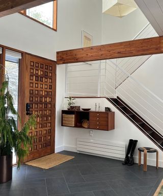 Mid-century modern entryway with slate flooring and wood tones on the door and shelving unit