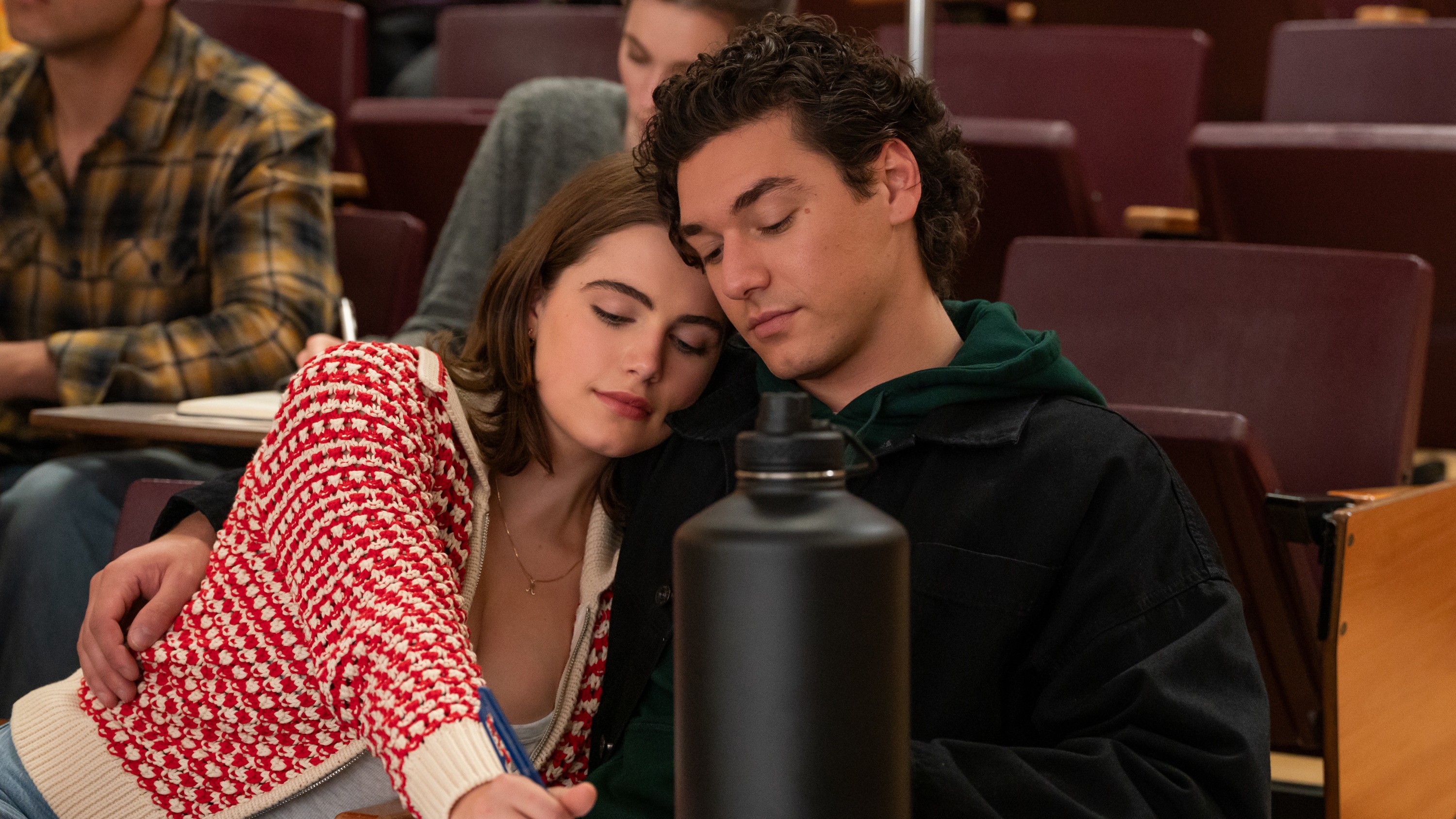 Hannah leaning her head on Garrett's shoulder as they work during a university class.