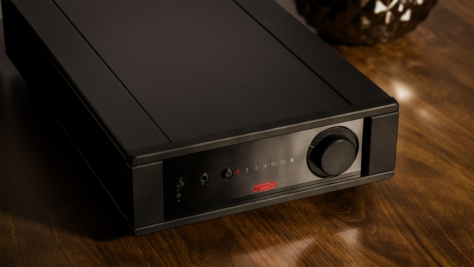A black Rega Brio Mk7 stereo amplifier on a wooden surface.