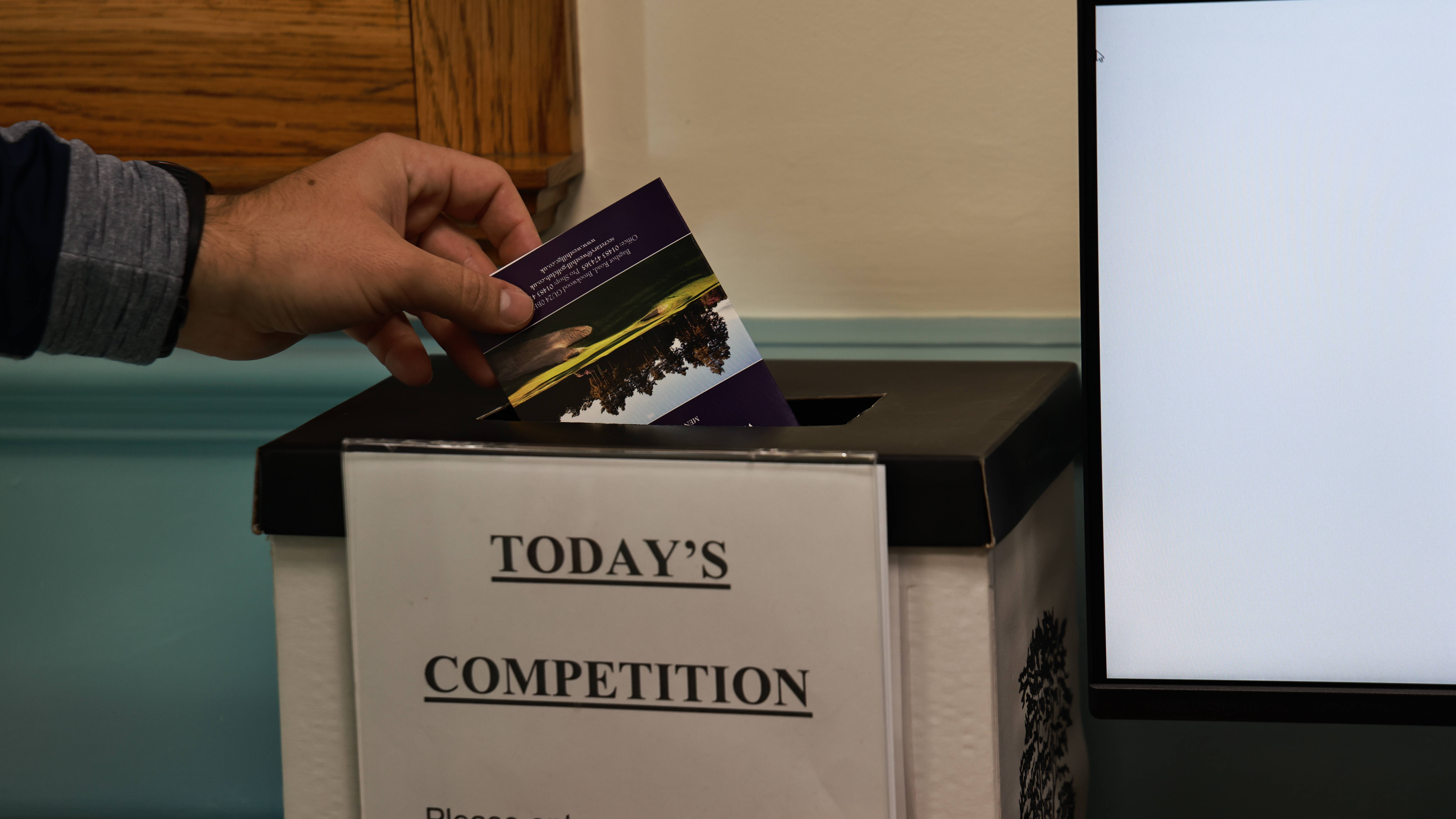 Golfer putting scorecard in competition box