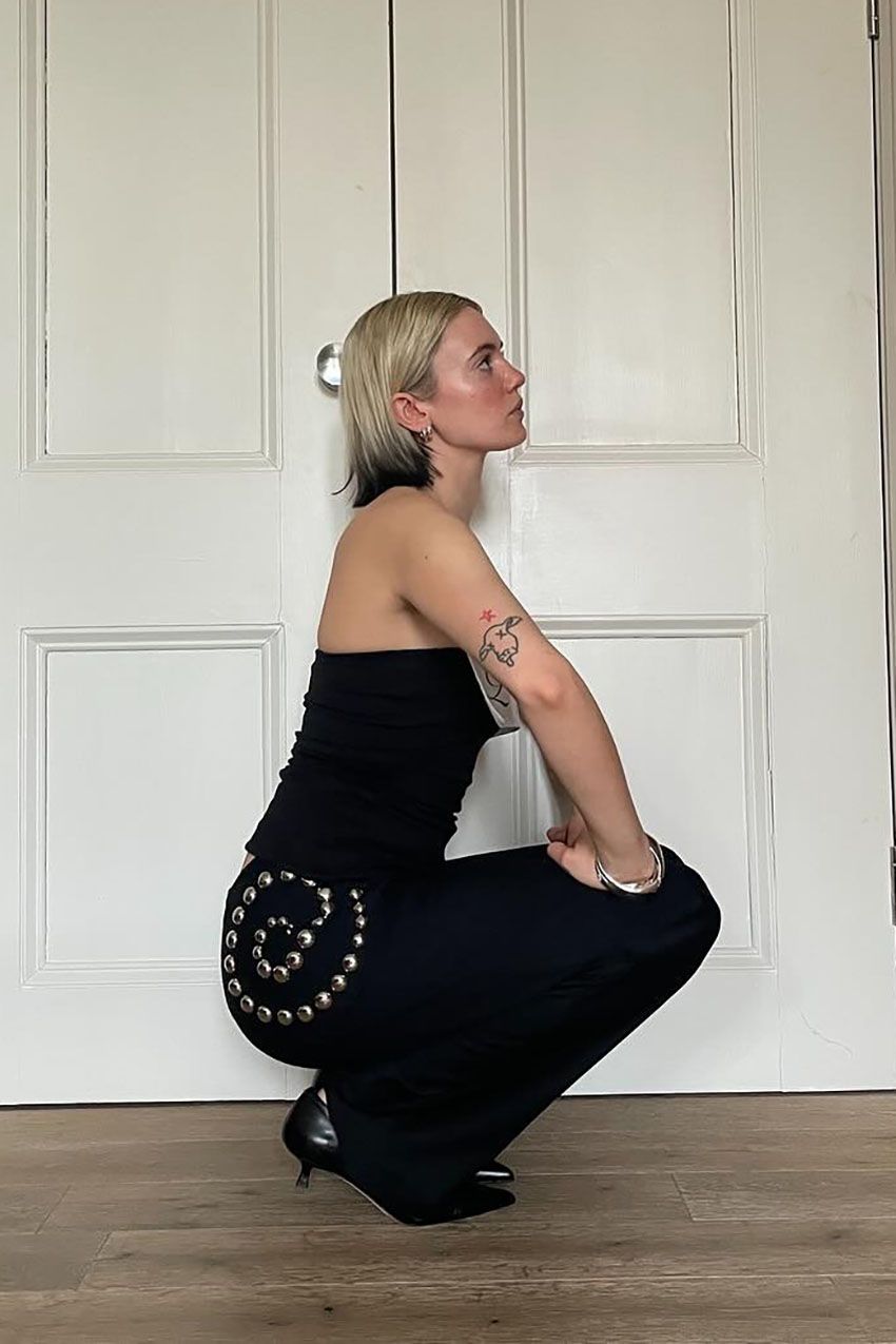 a woman wearing a black top and black pants with silver spiral embellishments