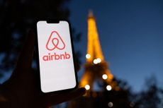 Airbnb logo on smartphone with blurred Eiffel Tower in the background