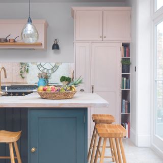 Pink and navy kitchen with shelving built into the side for books