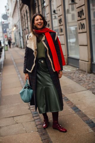 a woman stands on the street in Copenhagen wearing a shearling coat and skirt