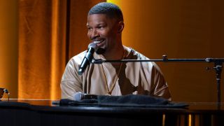 Jamie Foxx sitting at a piano smiling as he plays in Jamie Foxx: What Had Happened Was...