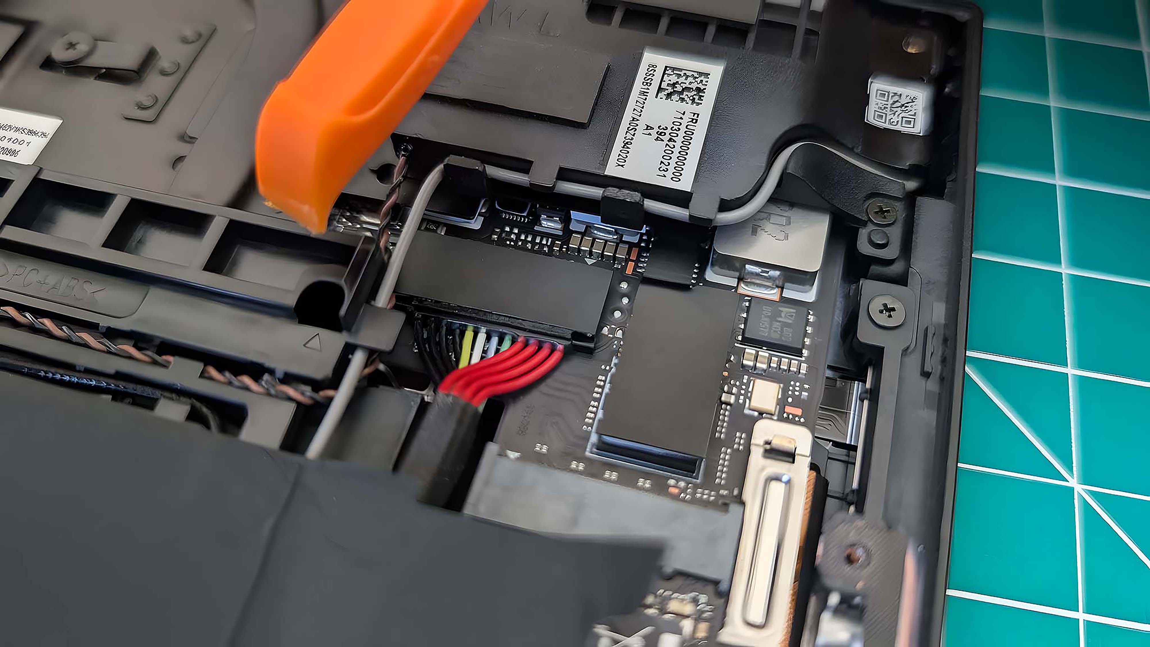 A prying tool hovering over the Lenovo Legion Go's battery cables.