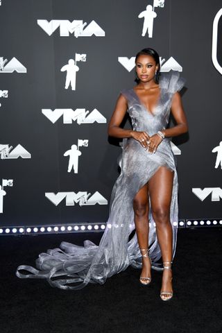 Coco Jones wears a silver dress with a thigh-high slit on the 2024 VMAs red carpet