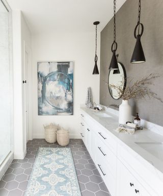 white bathroom with one taupe textured wallpaper accent wall, rug, white vanity, pendant light, shower on left