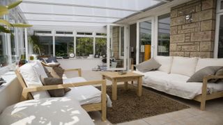 Neutral conservatory interior with overhead blinds and green garden view