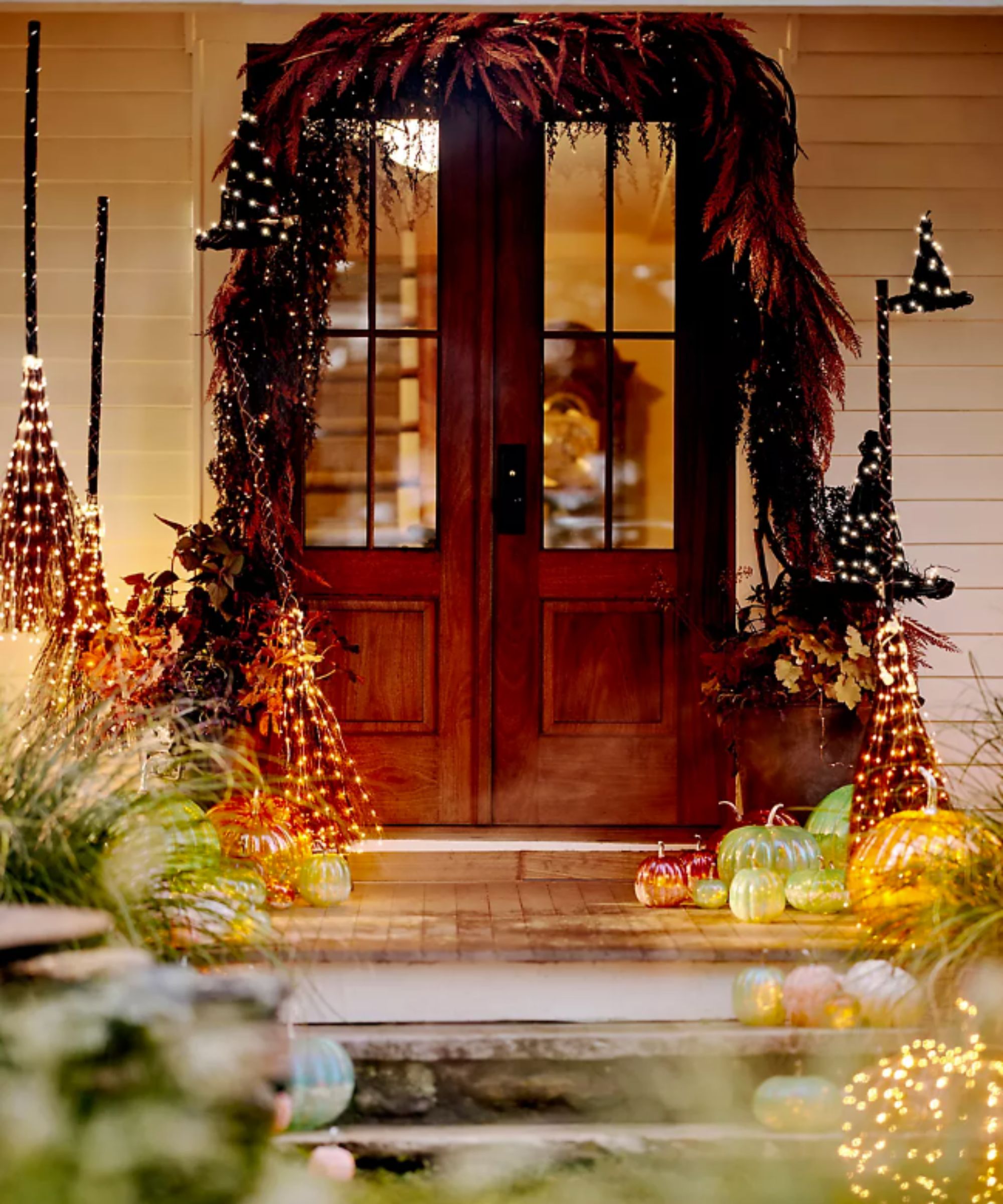 Porch decorated with light-up broomsticks, witch hats and pumpkins