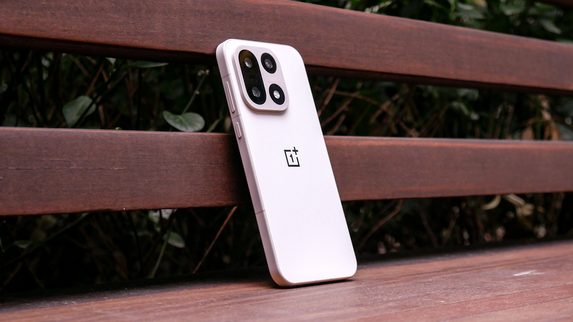 OnePlus 15 resting against wooden bench.