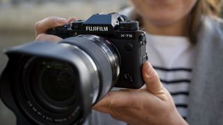 Fujifilm X-T5 with lens attached being held by reviewer Lauren Scott