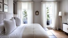 Bedroom with white sheets, white frill pillows and a taupe comforter