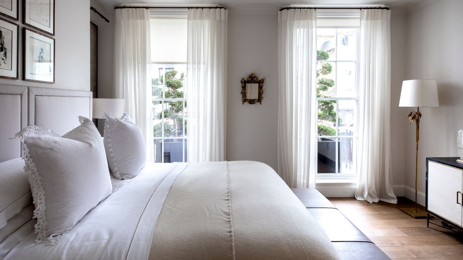 Bedroom with white sheets, white frill pillows and a taupe comforter