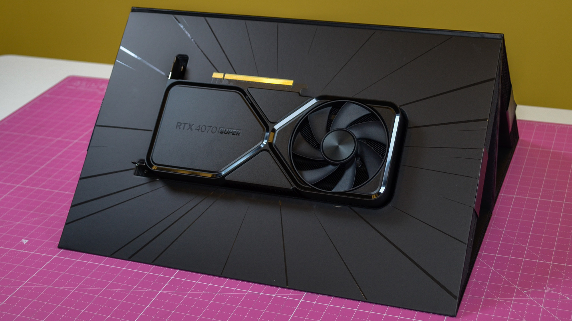 An Nvidia GeForce RTX 4070 Super on a desk in front of a yellow background