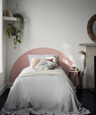 A white bedroom with pink paint DIY headboard decor and corner shelf with plants