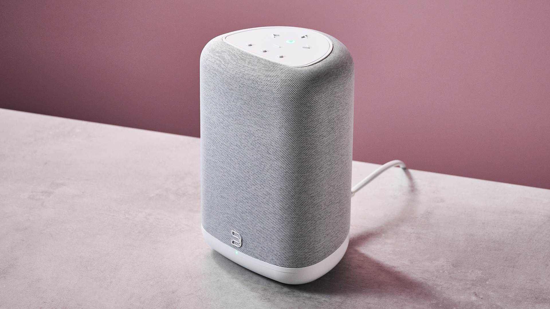 The Bluesound Pulse Flex from an overhead angle on a stone effect counter in front of a pink background.