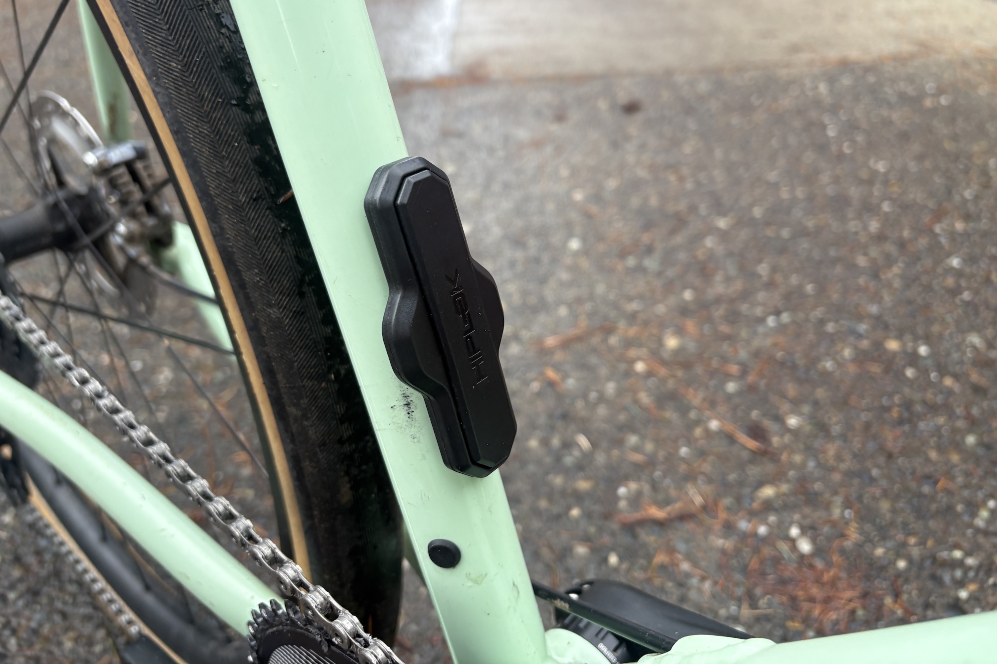 The hiplok track airtag holder mounted to the seat tube bottle cage mount of a mint coloured Rock Lobster gravel bike.