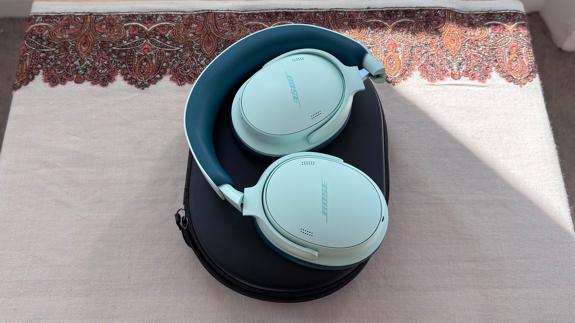 Bose QuietComfort Headphones (2nd Gen) over-ear headphones sitting on top of closed case on white/grey fabric