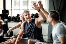 Athletes share a supportive high five while resting after rowing. 