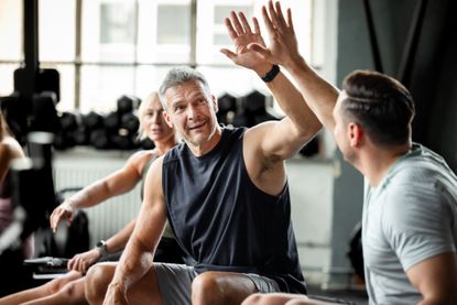 Athletes share a supportive high five while resting after rowing. 