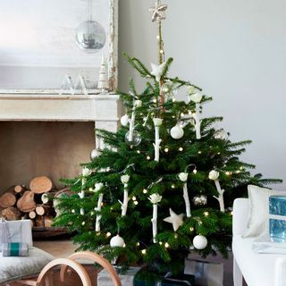 christmas tree with white ornaments and wood stack