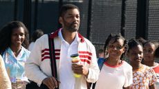 Will Smith in King Richard, alongside a crowd of people including his in-movie daughters