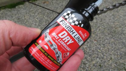 Male cyclist holding a bottle of Finish Line Dry Bike Lube