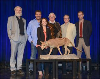 The panelists (from left to right) — George Church, Neil deGrasse Tyson, Beth Shapiro, Henry (Hank) Greely, Ross MacPhee and Gregory Kaebnick — stand in front of a thylacine, an extinct marsupial from Tasmania also known as the Tasmanian tiger.