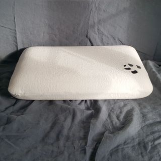 The Panda Memory Foam pillow being tested on a bed with grey bedlinen