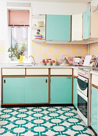 Retro kitschen trend interior in a kitchen with green and cream painted kitchen cabinets and pink and yellow tiles