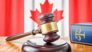 A gavel and a law book with a Canada flag on the background