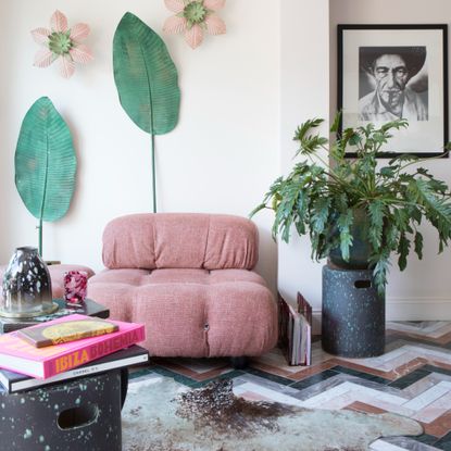 A snug with a patterned marble floor and a modular pink modern sofa with side tables used for displaying coffee table books and candles