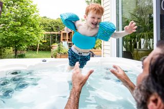 child wearing safety gear in hot tub with father