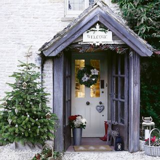 Christmas tree beside porch with white door and Christmas wreath