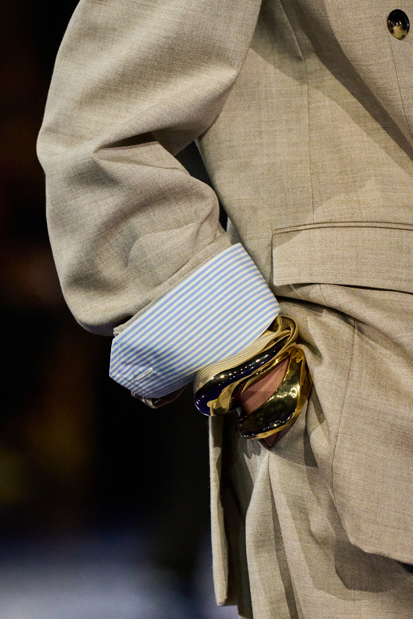 Saint Laurent runway a model wearing a tan suit and gold bracelets.