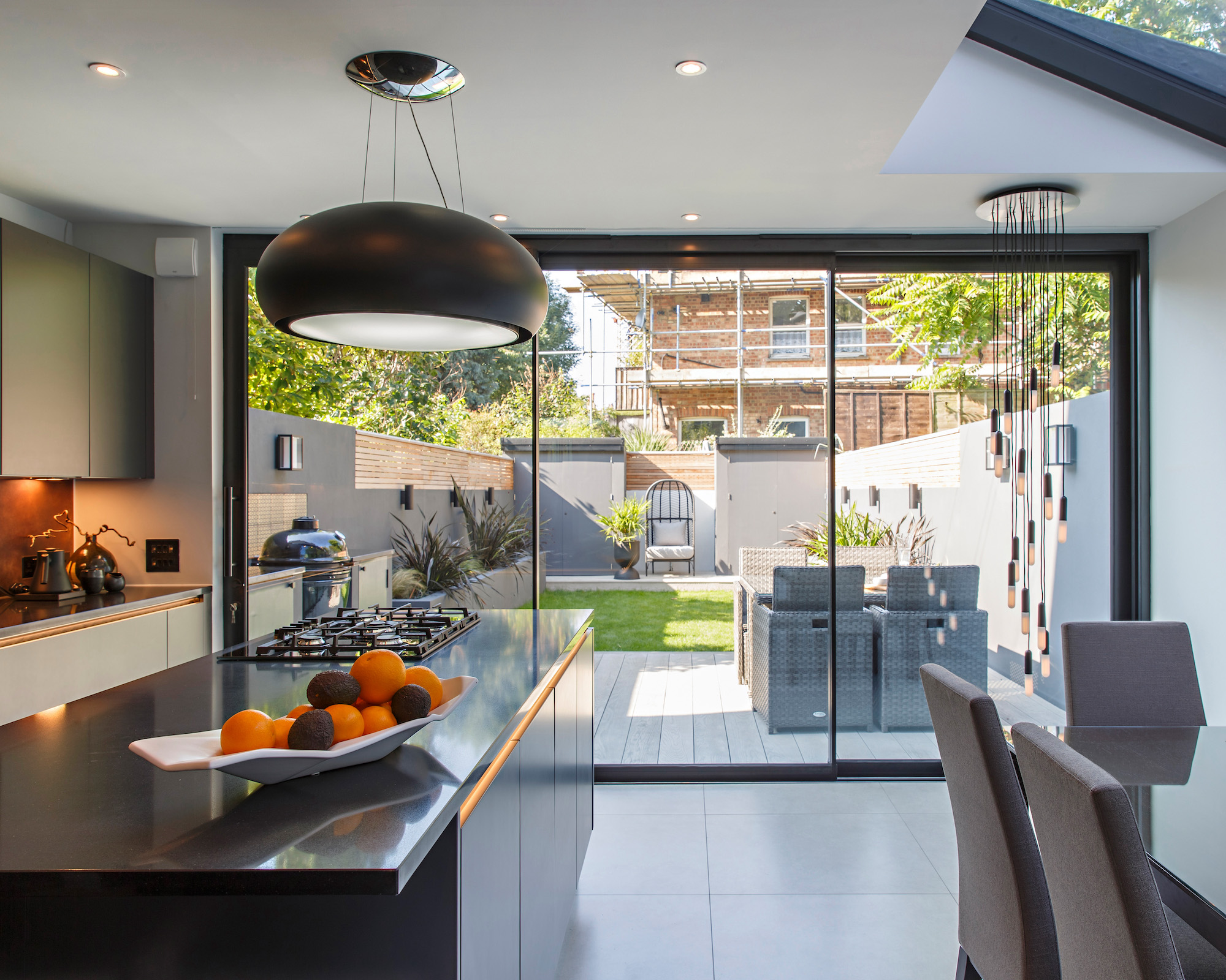 Kitchen-diner extension with large sliding doors onto patio and garden and house beyond with scaffolding
