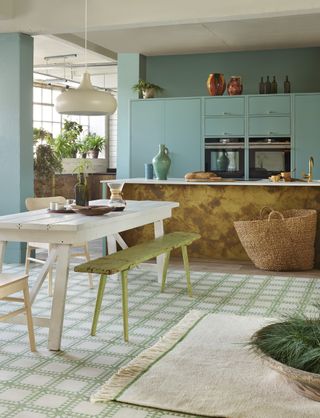 kitchen with mint green wall and metallic island are paired with patterned tiles and white table and chairs