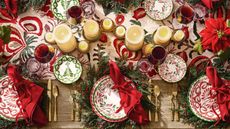 Christmas table with wreath chargers, green and red dinnerware, and gold cutlery