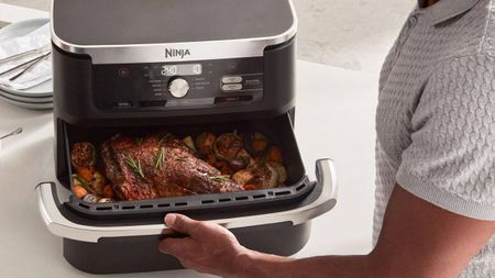 Someone using the Ninja Foodi FlexDrawer air fryer to cook a leg of lamb