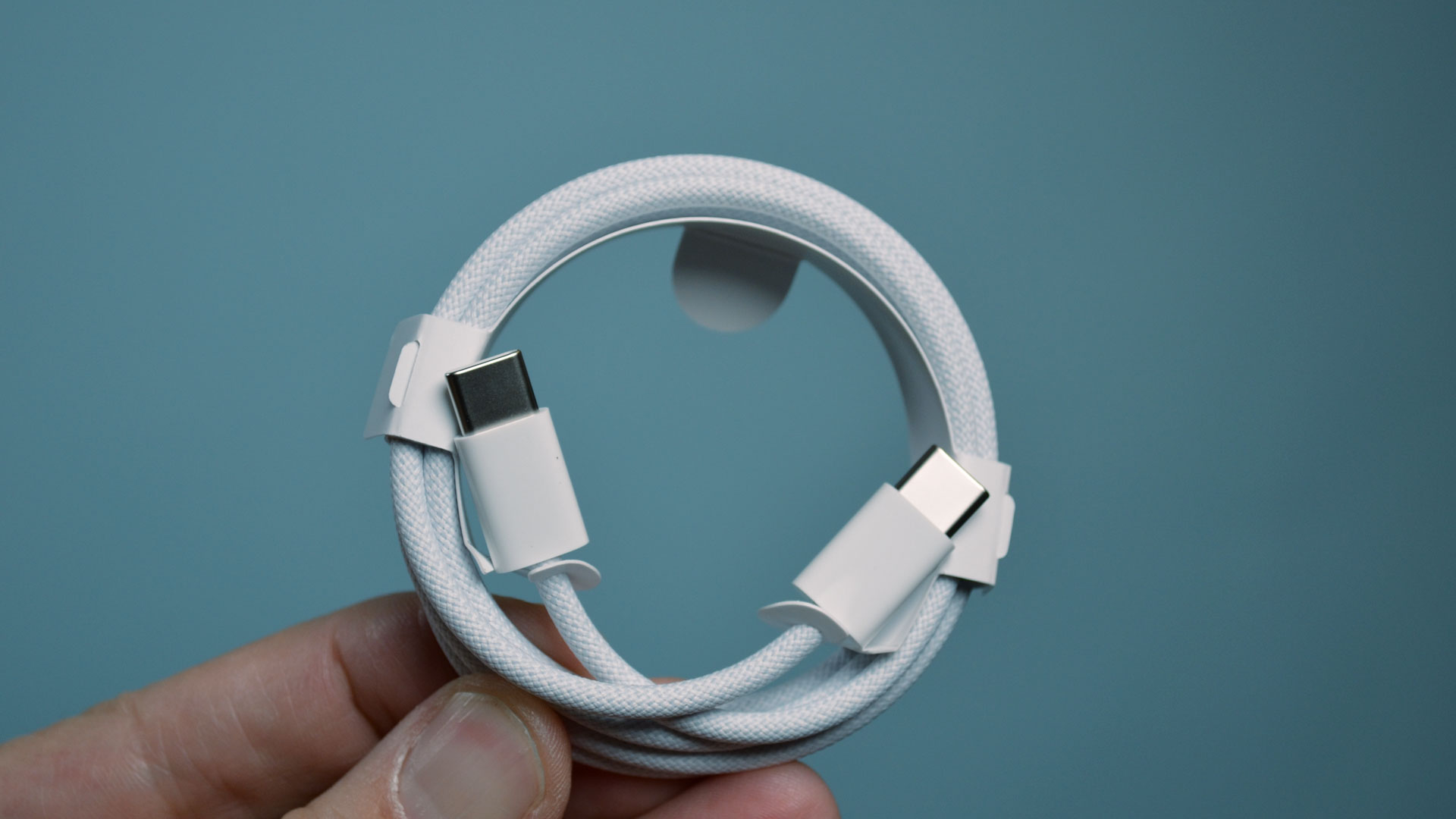 Den nye USB-C til USB-C-kabelen som leveres med Apple iPhone 15 Pro kveilet i en hånd.