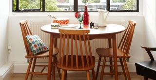 Retro 70s wooden dining table and chairs in front of a crittal window in a dining room